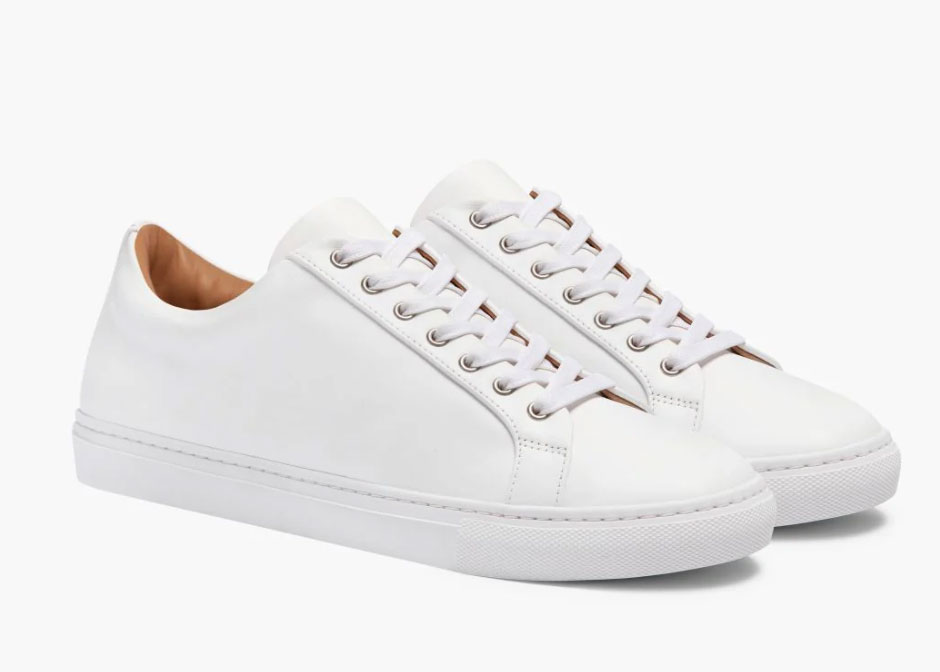 10-Sneakers - Style Fix Studio Pair of white low-top sneakers with white laces and rubber sole, shown in a side angle