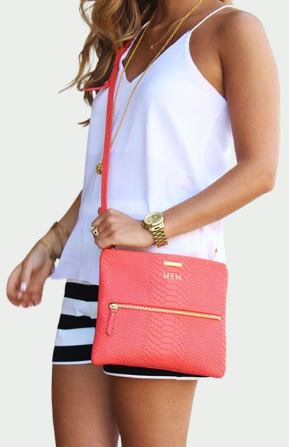 12-Cross-Body-Bag - Style Fix Studio Woman in a white tank top and striped shorts wearing a coral crossbody bag with a gold zipper at hip.