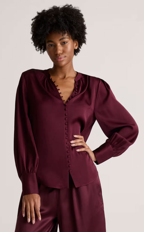 7A-Silk-Blouse-Burgundy - Style Fix Studio Model wearing a burgundy satin blouse with puff sleeves and matching pants, standing with one hand on hip in a neutral studio setting